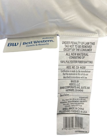 A close-up of a mattress tag indicating the Best Western<sup>®</sup> Aurora Pillow | Medium Polyester Pillow's compliance with law, materials (polyester fiberfill), and manufacturer info with a Keeco branding, suggesting the mattress is from a hotel.
