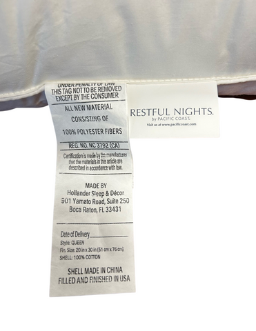 A close-up of a white Restful Nights Renova™ Pillow's care tags indicating 100% Renova® Recycled fiber filling, the restfulnights.com website, and manufacturing details including size, style, and origin
