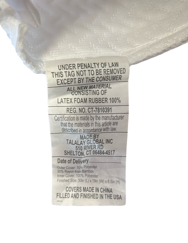 A close-up of a Latex International Rejuvenite Classic High Profile Pillow label specifying the materials—100% Natural Latex Foam—and providing manufacturer details, cautioning against removal under penalty of law, except by the consumer.