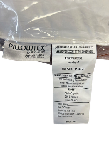 A close-up view of a Pillowtex Premium Polyester Pillow law tag on an overstuffed polyester fiber pillow, illustrating mandatory consumer information such as content, manufacturer details, and care instructions.