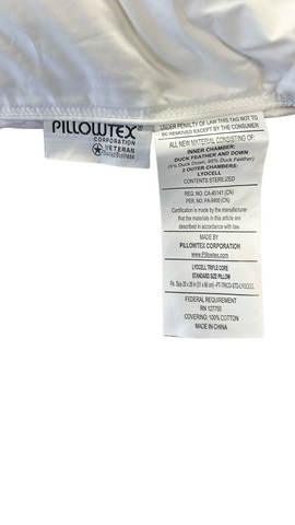 A close-up image of a white Pillowtex Triple Core Lyocell Pillow label from Pillowtex Corporation listing material contents, care instructions, and manufacturing details. The label specifies duck feather and down content with a background of silky white fabric on.
