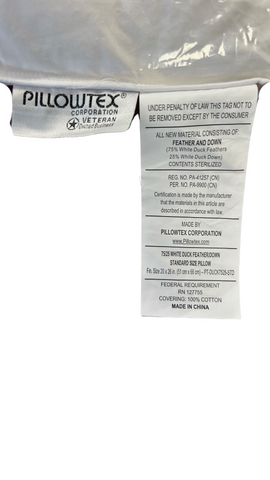 A close-up of a Pillowtex® White Duck Down & Feather Pillow tag under translucent plastic packaging. The tag includes legal warnings, material content (70% feathers, 30% down), care instructions, and compliance with standards.