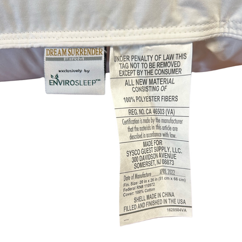 Close-up of a Envirosleep Dream Surrender Firm Pillow label by Manchester Mills, showing care instructions, material composition (100% polyester), certification, manufacturer details, and origin (made in China).