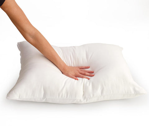 A person's arm presses down on a Carpenter Dual Layered Comfort Pillow | Medium Support to test its softness and resilience, isolated on a white background.