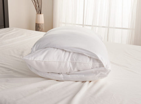 A Carpenter Co. Dual Layered Comfort Pillow | Extra-Firm Support is laying on top of a bed.