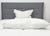A neatly made bed with a gray headboard features the Pillowtex Triple Core White Duck Down & Feather Pillow, offering medium-soft support, on crisp white bedding—perfect for side and back sleepers seeking a hotel-quality rest.