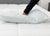 Wearing a long-sleeved black shirt, a person presses their hand into the white JS Fiber Hollofil II Pillow | Medium by JS Fiber on a quilted mattress, showing the hypoallergenic pillow's softness and responsive indentation.