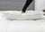 A hand presses down on the JS Fiber Super Gold Choice Pillow | Heavyweight by JS Fiber, featuring yellow piping and siliconized fiberfill, resting on a white quilted mattress with a gray upholstered headboard—ideal for side sleepers.
