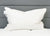 The Pillowtex Triple Core White Duck Down & Feather Pillow, offering medium-soft support, is shown upright on a white mattress with a gray upholstered headboard, creating a clean, modern look. Perfect for side and back sleepers.