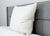 The Down Etc. Fairfax Pillow—featured at St. Julien Hotel & Spa®—rests upright on a modern gray headboard, offering firm support for side and back sleepers while creating a clean, minimal bedroom look.
