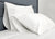 A Pillowtex Cotton Pillowcase Set (2 pillowcases) in white adds comfort to the bed, paired with a white comforter and placed against a gray upholstered headboard for a clean, minimalist look.