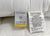 Two tags are attached to the white Envirosleep Gold Plus Pillow by Manchester Mills. The left tag shows the brand and product name, while the right lists it as a firm, hypoallergenic 100% polyester pillow made in Pakistan with legal info in black on white.