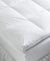 A plush, white Chaps Baffle Box Feather Bed mattress topper with square stitching lies on a bed, promising added comfort and support and a luxurious feel to enhance sleep quality. Made in the USA by Hollander.