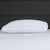 The Carpenter Comfort Tech Bed Pillow Featuring Tranquility Foam in white with a subtle texture rests on matching bedding, complemented by a dark gray upholstered headboard that contrasts and highlights the clean, crisp look.