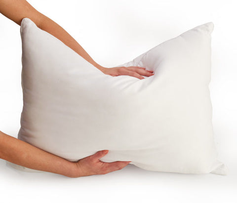 A person's hands are squeezing a Carpenter Co. Dual Layered Comfort Pillow, demonstrating its softness and fluffiness against a seamless white background.