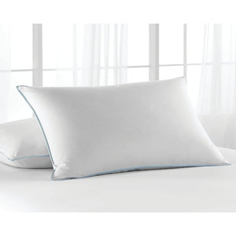 A white rectangular Hollander hotel pillow with a subtle blue piped edge rests against a light and airy backdrop, suggesting a serene and comfortable sleeping environment.