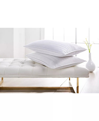 Two Stearns & Foster Down Halo Pillows™ | 600 Fill Power are stacked atop a sleek, tufted daybed with a wooden frame, set in a bright, minimalist room with a single vase holding fresh tulips.