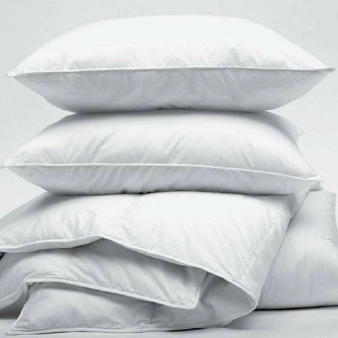 A stack of fluffy white JS Fiber Gold Choice Polyester Pillows against a grey background, suggesting softness and comfort with their hollow siliconized fiberfill for a peaceful sleep environment in hotel franchise properties.