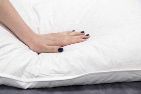 The woman's feet rest on a Pillowtex White Goose Feather and Down Body Pillow for comfort.