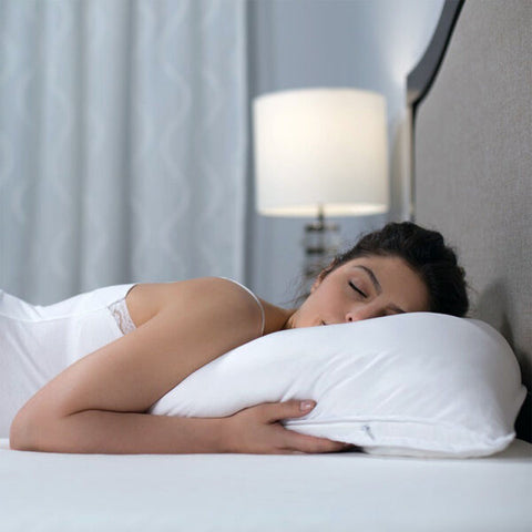 A woman sleeping on a bed with a Protect-A-Bed Adjustable Fill Luxury Waterproof Tencel Lyocell Pillow.