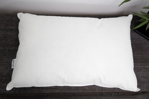 A Pillowtex White Goose Down & Feather Pillow for neck support on a wooden table.
