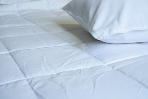 A bed with white sheets and pillows made from Manchester Mills Down Dreams Asheville Down Comforter, featuring a Baffle Box Design and Lightweight comfort.