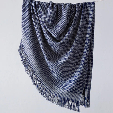 A cozy Fairkind Alta Mar Alpaca Throw in blue and white checkered pattern hanging on a hanger.