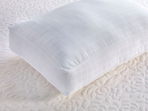 A white Carpenter Co. Beyond Down Side Sleeper Pillow is placed on a bed.