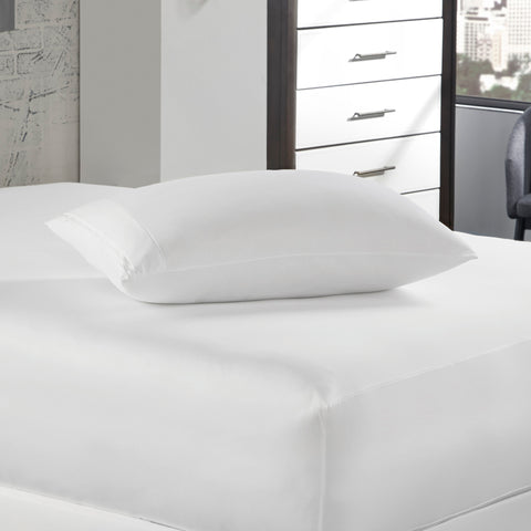 A white bed with a PureCare Luxury Resort Hotel Collection Pillow Protector on top of it for protection against allergens and bed bugs.