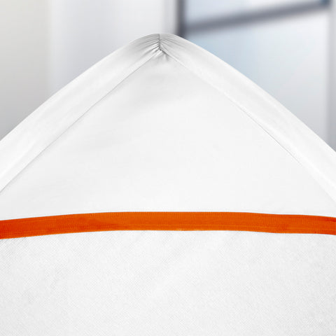 A close-up of a white bed with an orange stripe, featuring a PureCare ReversaTemp 5-Sided Mattress Protector for temperature control.