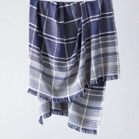 A Fairkind Escalante Alpaca Throw in blue and white plaid is hanging on a hanger.