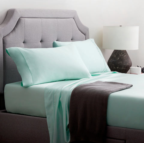 A bed with Malouf Tencel Pillowcase Set and a gray headboard.
