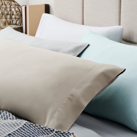A bed with two Malouf Bamboo Pillowcase Sets and a blanket on it.