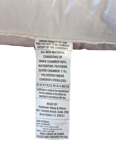 A law label is sewn onto a Hollander Opulence Superside Gussetted Feather Chamber Pillow, disclosing content information such as "89% polyester fibers," with manufacturing and compliance details, indicating it's made in China and finished in the USA.