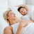 A man and woman lay in bed with their eyes closed, enjoying the comfort of JS Fiber Hollofil II Pillow | Medium bedding by JS Fiber.