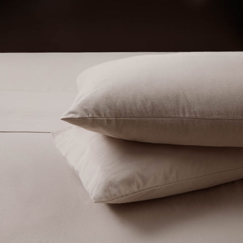 Two durable Malouf Portuguese Flannel Pillowcase Sets stacked on top of a bed.