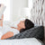 A woman laying in bed reading a book with a Z Wedge Pillow by Malouf.