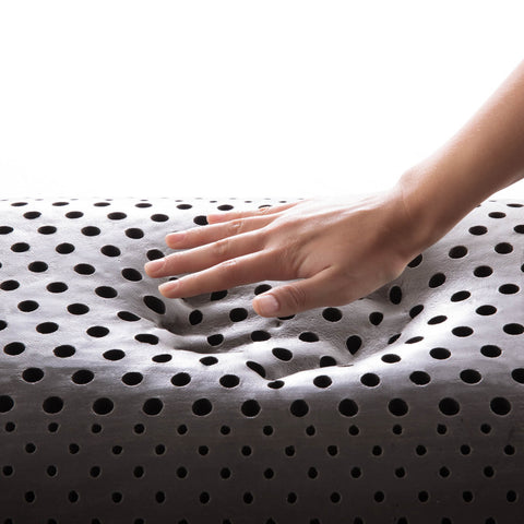 A hand touching a Malouf Zoned ActiveDough™ + Bamboo Charcoal Pillow, possibly triggering allergies or asthma.