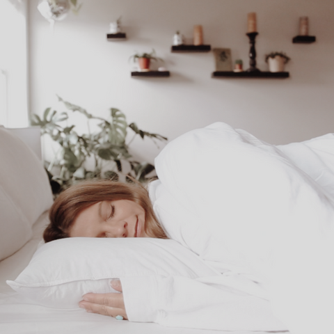 A woman sleeping in a white blanket on a bed with Down Dreams Classic Soft Pillows by Manchester Mills.