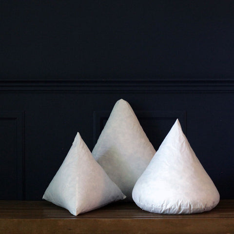 Three Down Etc. Decorative Pillow Insert | Pyramid pillows on a wooden table.