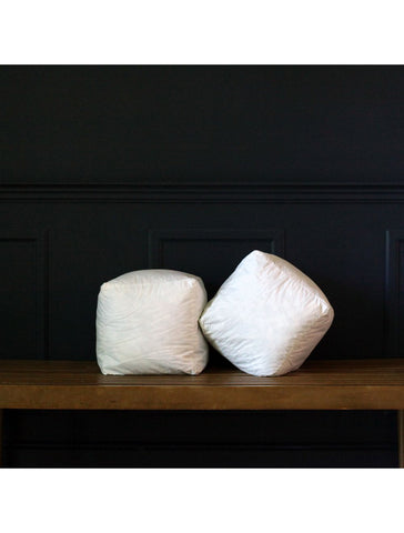 Two Down Etc. Decorative Pillow Insert | Cubes on a wooden bench in front of a black wall.