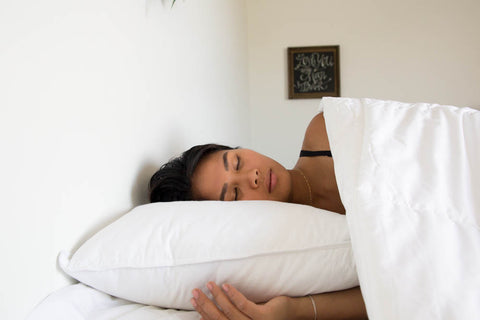 A woman laying in bed with a Down Etc. Diamond Support Feather & Down Pillow | Medium-Firm for support under her head.