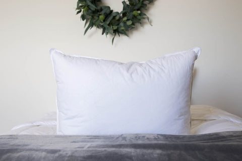 A white Down Etc. Diamond Support Feather & Down Pillow | Medium-Firm on the bed with feathers in it.