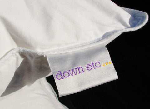 A white pillow with a label that says Down Etc.