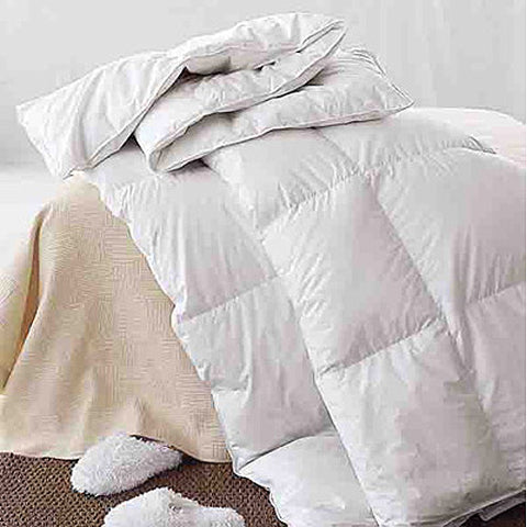 A Downlite Premium White Goose Down Baffle Box Comforter-King on a bed with a pair of slippers.