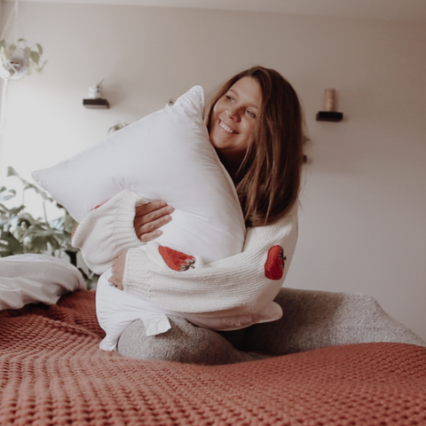 A woman embracing a Envirosleep Dream Surrender Firm Pillow, Formerly Dream Surrender Two by Manchester Mills on a bed at a hotel property.