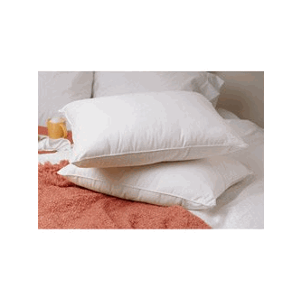 Two plush white JS Fiber Quallofil Pillows rest atop each other on a terracotta-colored, textured blanket, adjacent to a small glass jar with a gold lid, alluding to a cozy and stylish atmosphere.