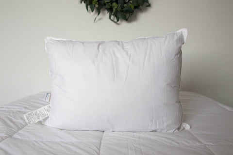 An Manchester Mills Envirosleep Dream Surrender Polyester Pillow rests on the bed, providing medium support with its polyester clusters.