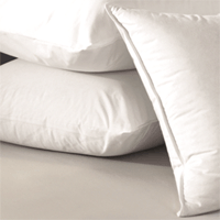Three Envirosleep Platinum Garneted Polyester Fiber Fill Pillows by Manchester Mills stacked on top of each other, made with recycled polyester fibers for an environmentally friendly option.