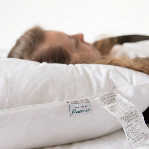 A woman is peacefully sleeping on a Manchester Mills Envirosleep Dream Surrender Polyester Pillow | Medium Support.